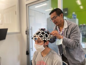 Someone fitting an EEG cap on a student