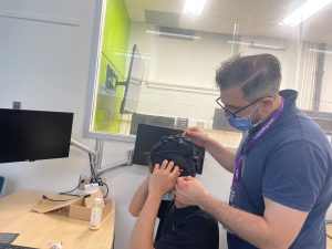 Someone fitting an EEG cap on a student