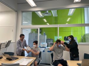 Two people helping two students put on an EEG cap