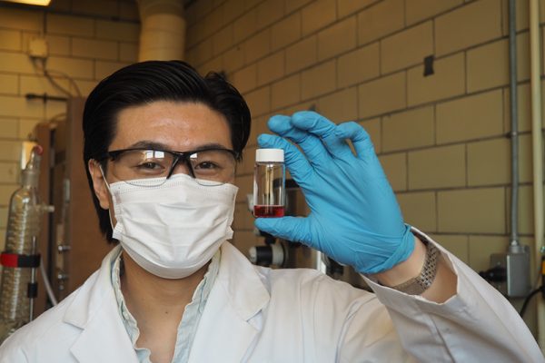 Paul Chen holding a small vial of red liquid.